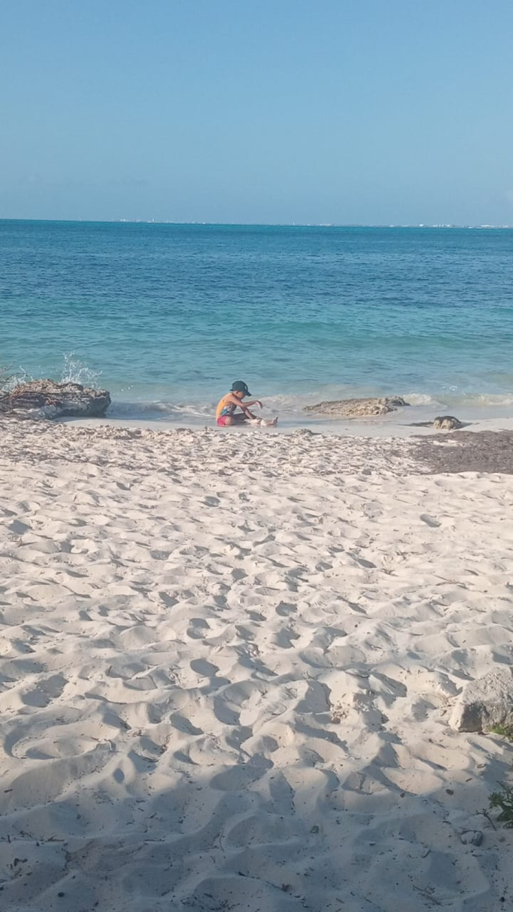 niño haciendo un castillo de arena en pla playa de cancun con el sol turquesa